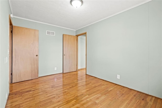 unfurnished bedroom featuring visible vents, crown molding, and wood finished floors