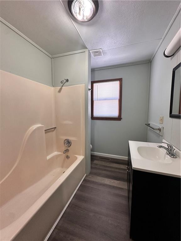 full bath with visible vents, toilet, wood finished floors, a textured ceiling, and vanity