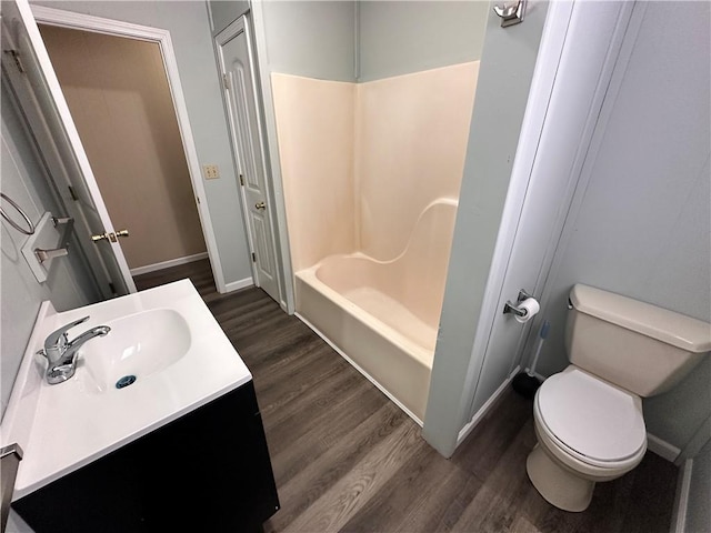 bathroom featuring baseboards, toilet, wood finished floors,  shower combination, and vanity