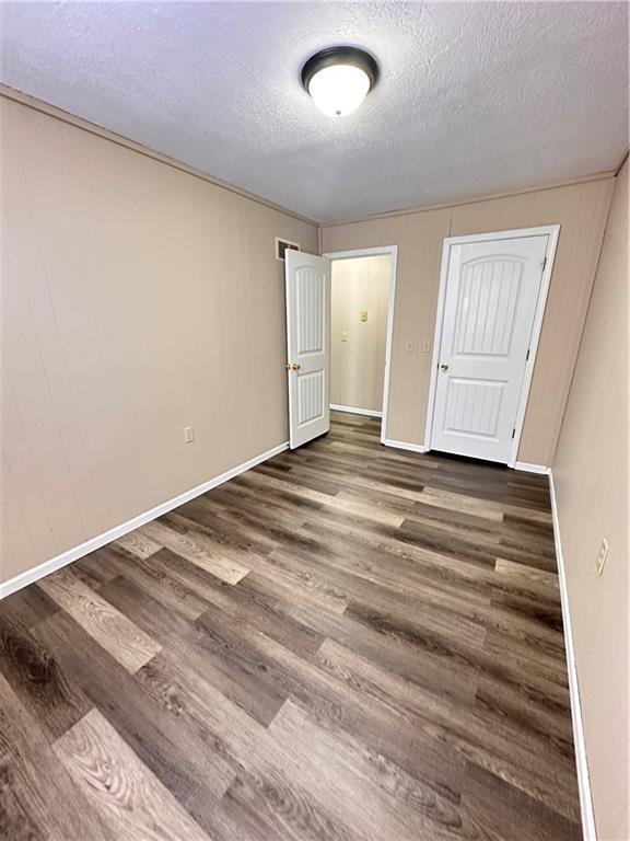 unfurnished bedroom with visible vents, a textured ceiling, baseboards, and wood finished floors