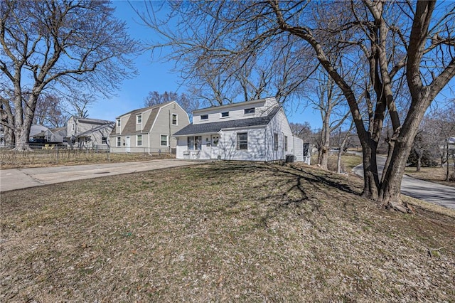 view of front of property with a residential view, concrete driveway, a front yard, and fence