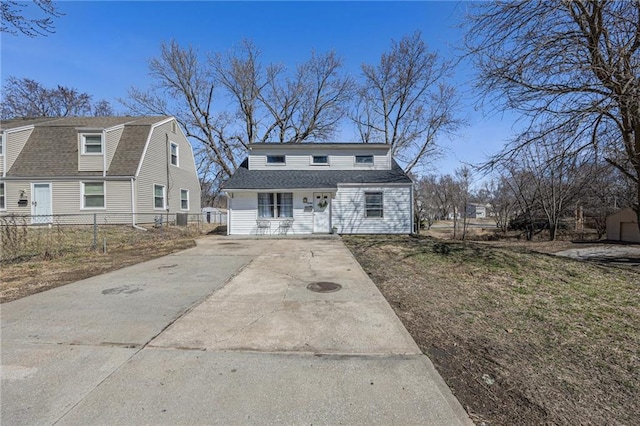 dutch colonial with a gambrel roof, a shingled roof, and fence