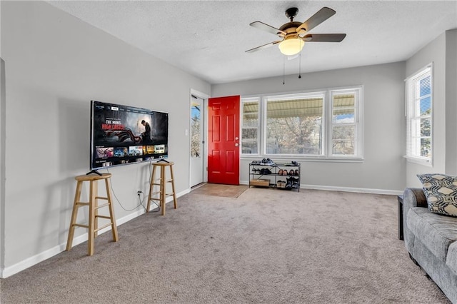 living room featuring a ceiling fan, baseboards, carpet floors, and a textured ceiling