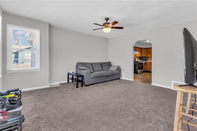 living room with visible vents, a ceiling fan, arched walkways, baseboards, and light colored carpet