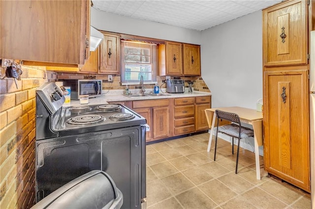 kitchen featuring light countertops, electric range, brown cabinetry, and a sink