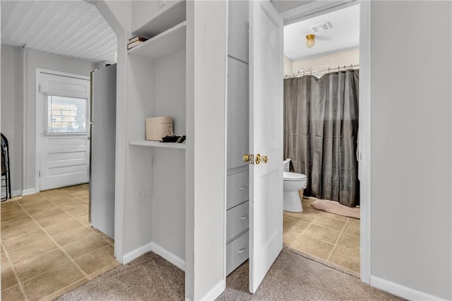 bathroom featuring tile patterned flooring, a shower with shower curtain, toilet, and baseboards