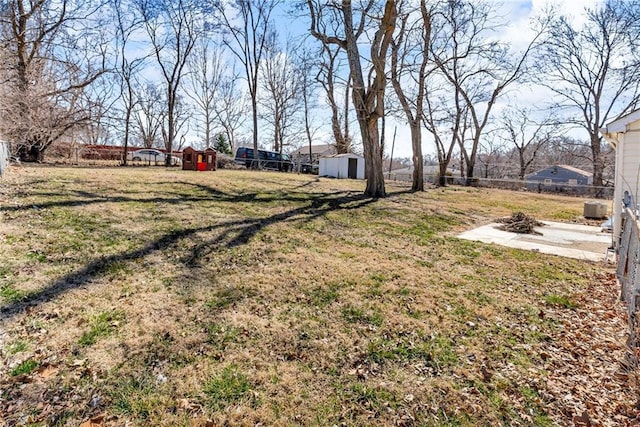 view of yard featuring a fire pit, a storage unit, an outdoor structure, and fence