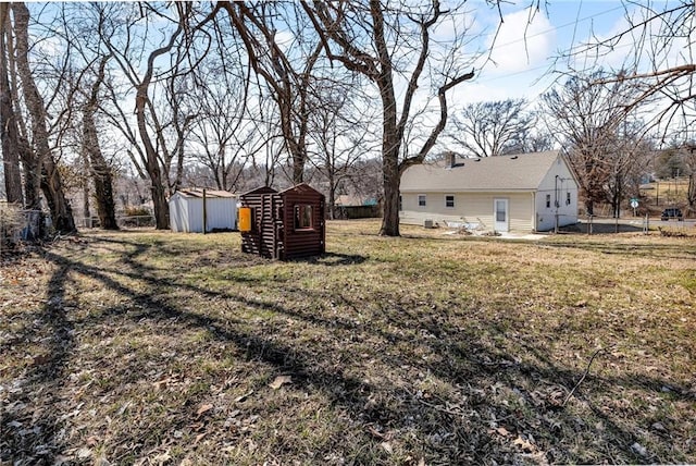 view of yard featuring an outbuilding, a storage unit, and fence