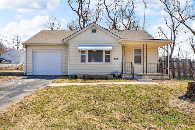 view of front of house with fence, roof with shingles, an attached garage, a front lawn, and aphalt driveway