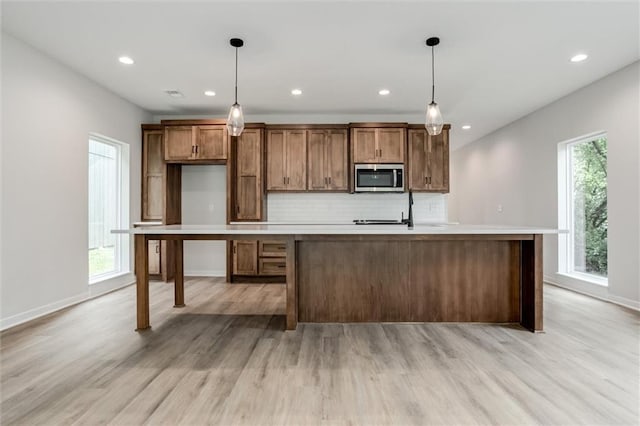 3322 Tracy Ave, Kansas City, MO 64109 - kitchen featuring stainless steel microwave, light wood-type flooring, tasteful backsplash, light countertops, and recessed lighting