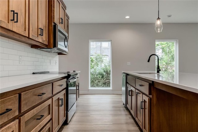 3322 Tracy Ave, Kansas City, MO 64109 - kitchen with stainless steel appliances, a sink, decorative backsplash, light wood finished floors, and recessed lighting