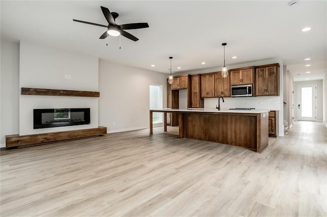 3322 Tracy Ave, Kansas City, MO 64109 - kitchen with stainless steel microwave, light wood-style floors, a glass covered fireplace, baseboards, and recessed lighting