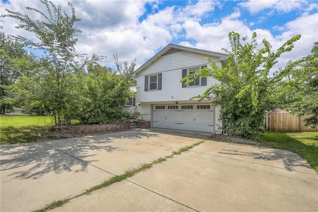 view of side of property featuring a garage, driveway, and fence