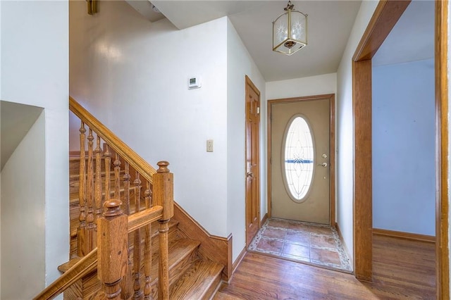 foyer entrance with stairway, baseboards, and wood finished floors