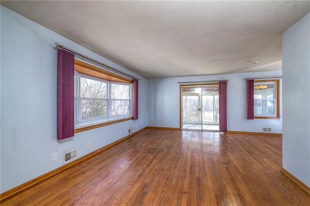 empty room with visible vents, baseboards, and wood finished floors