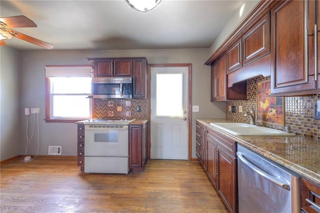 kitchen with visible vents, stainless steel appliances, wood finished floors, and a sink