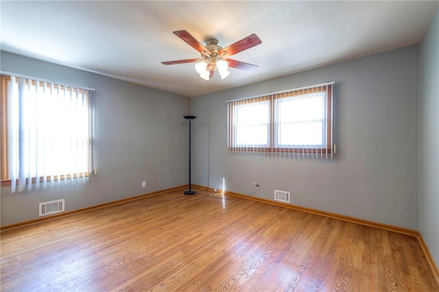 empty room with visible vents, baseboards, light wood-type flooring, and a ceiling fan