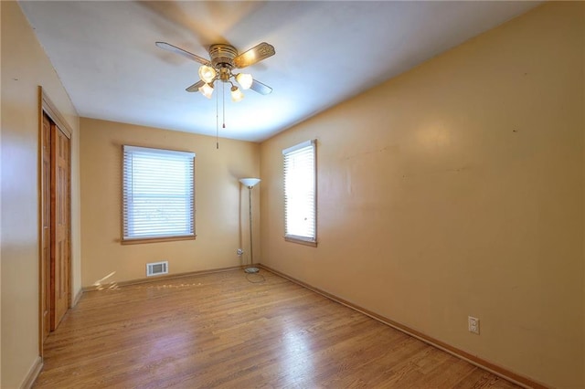 empty room featuring visible vents, light wood-style flooring, and a ceiling fan