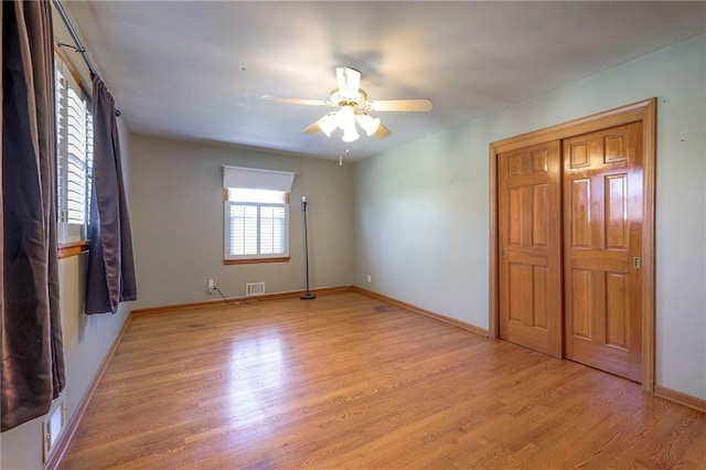 unfurnished bedroom with light wood finished floors, visible vents, ceiling fan, and baseboards