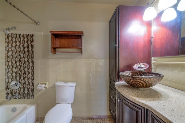 bathroom with tile walls, toilet, shower / bathing tub combination, vanity, and speckled floor