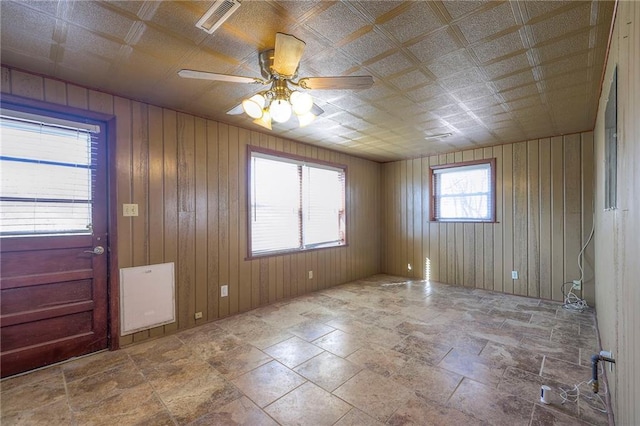 foyer featuring visible vents, ceiling fan, and wooden walls