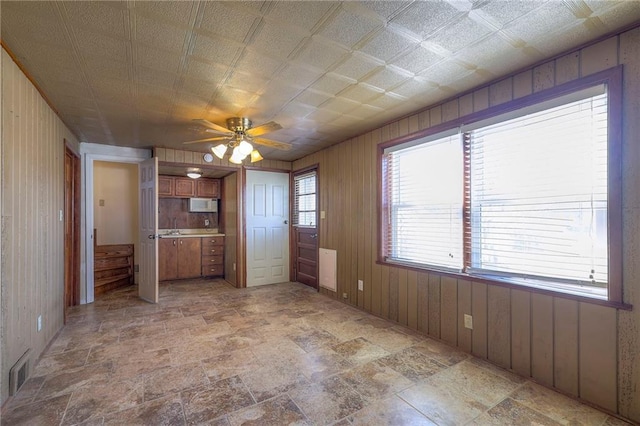 kitchen featuring visible vents, wood walls, and stone finish flooring