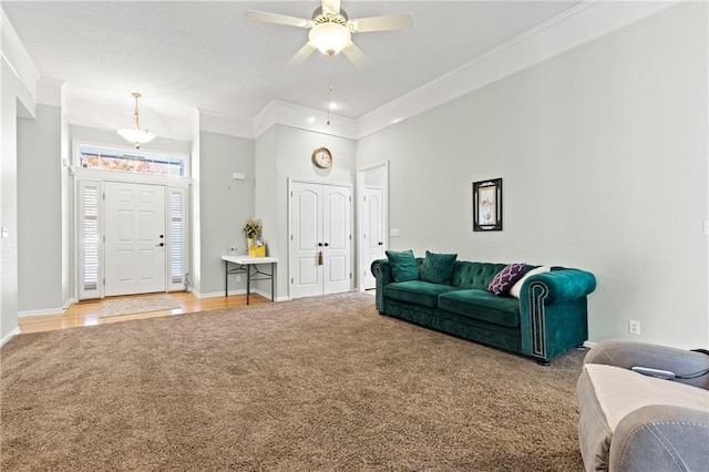 living area featuring light carpet, ceiling fan, ornamental molding, and baseboards