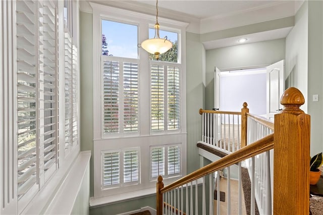 hallway with an upstairs landing and crown molding