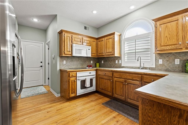 kitchen with white appliances, light wood finished floors, visible vents, light countertops, and a sink