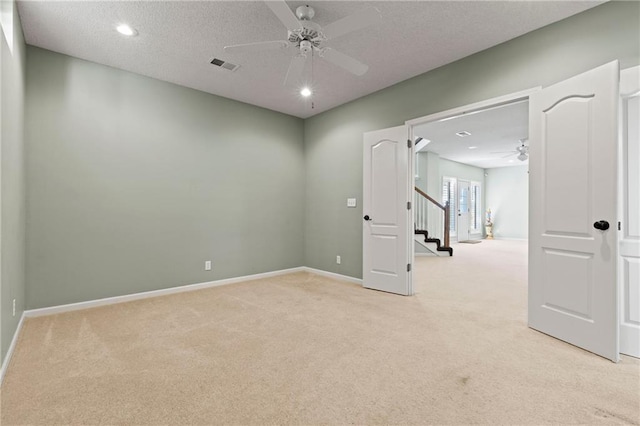 spare room featuring a ceiling fan, light colored carpet, visible vents, and baseboards