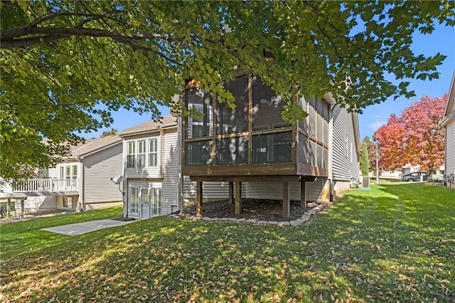 back of property with a sunroom and a lawn