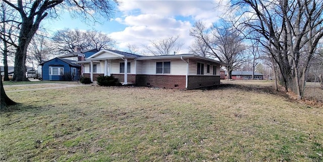 view of side of home with a porch, brick siding, and a yard