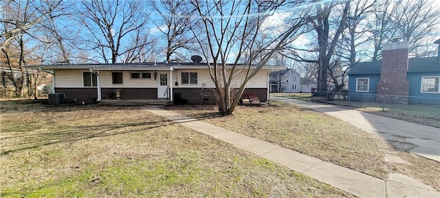 ranch-style house featuring covered porch, central AC, brick siding, and a front yard