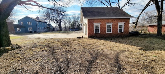 view of side of property featuring brick siding and fence