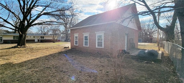 view of home's exterior with a yard, fence, and brick siding