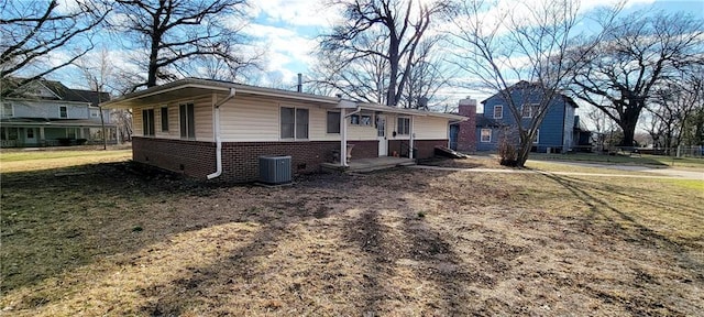 view of front of home with a front yard, central AC, and brick siding