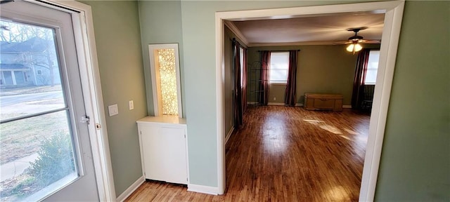 hall featuring ornamental molding, light wood-type flooring, and baseboards