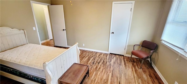 bedroom with light wood-type flooring, multiple windows, and baseboards