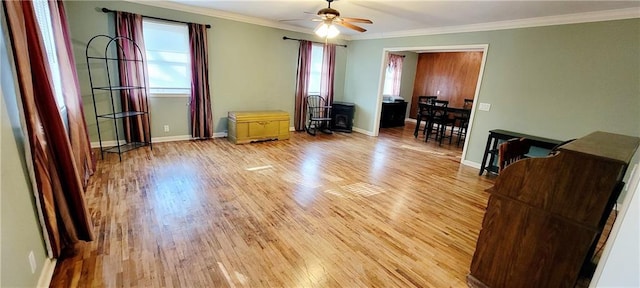 interior space with crown molding, light wood-type flooring, a ceiling fan, and baseboards