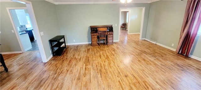 interior space with light wood-style floors, baseboards, and ornamental molding