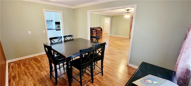 dining room with light wood-type flooring, baseboards, and ornamental molding