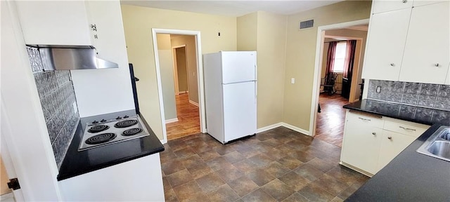 kitchen featuring visible vents, dark countertops, freestanding refrigerator, extractor fan, and electric stovetop