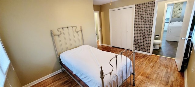 bedroom with washer / clothes dryer, a closet, wood finished floors, and baseboards