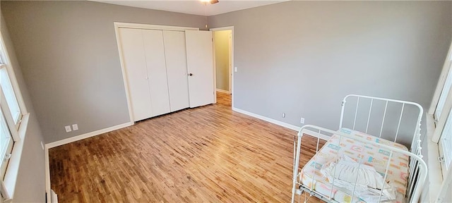 unfurnished bedroom featuring a closet, wood finished floors, and baseboards