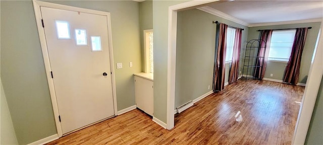 foyer featuring light wood-style flooring, a baseboard heating unit, baseboards, and ornamental molding