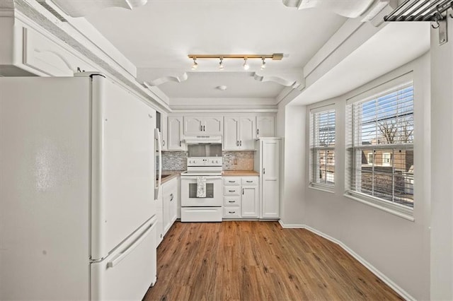 kitchen featuring under cabinet range hood, decorative backsplash, wood finished floors, white cabinets, and white appliances