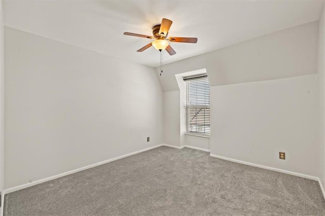 carpeted spare room with baseboards, ceiling fan, and vaulted ceiling