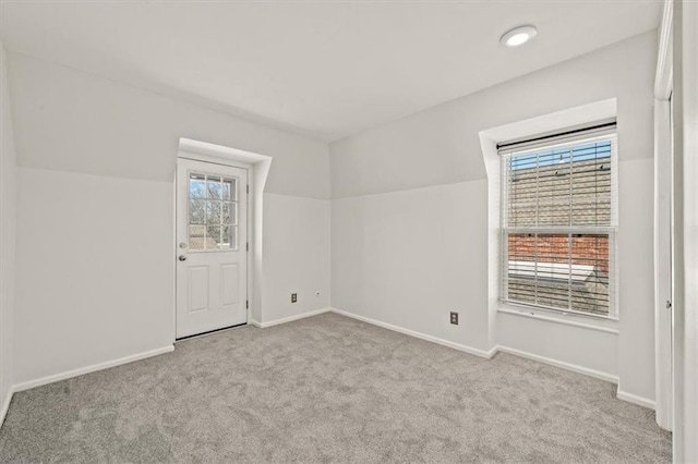 empty room featuring baseboards, carpet, and vaulted ceiling