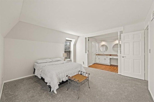 bedroom featuring a sink, baseboards, carpet flooring, and vaulted ceiling