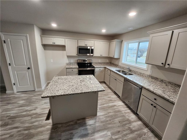 kitchen with light wood-style flooring, a kitchen island, appliances with stainless steel finishes, a sink, and recessed lighting